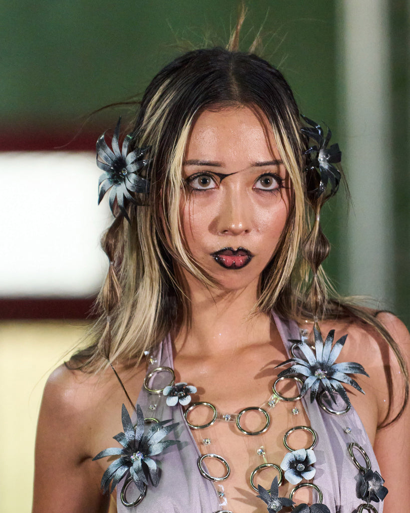 Model wearing a unique black and white floral cape daisy flower earring made from leather and a top made from more black and white flowers
