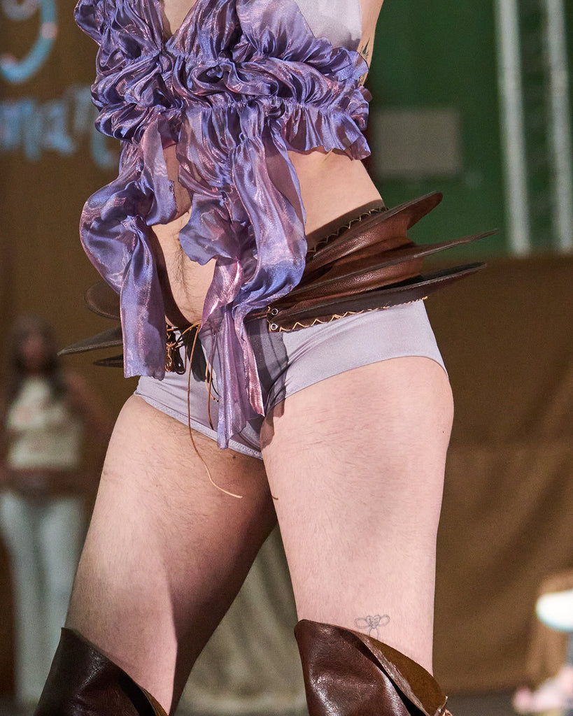 close up of model wearing a brown leather cowboy hip fin gills with lacing at the front and back
