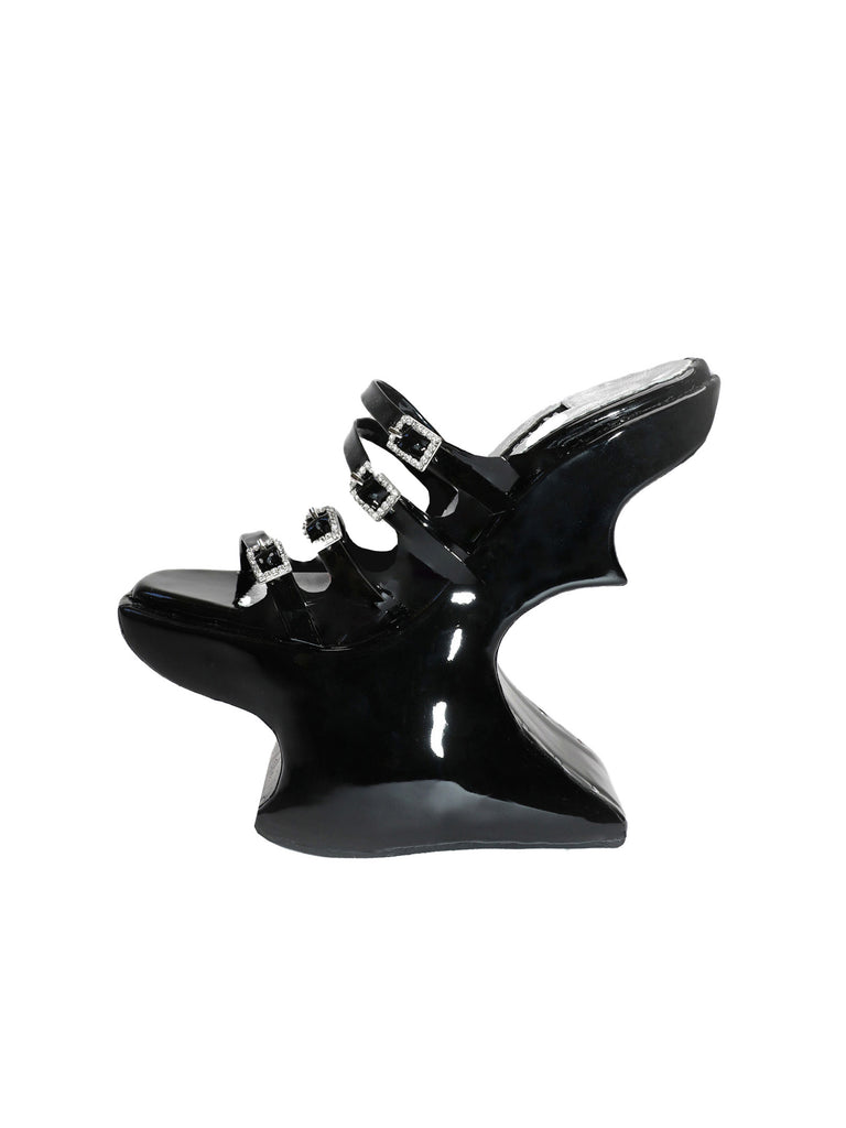 Black high-heeled shoe with four straps made from patent leather with a unique platform design on a white background