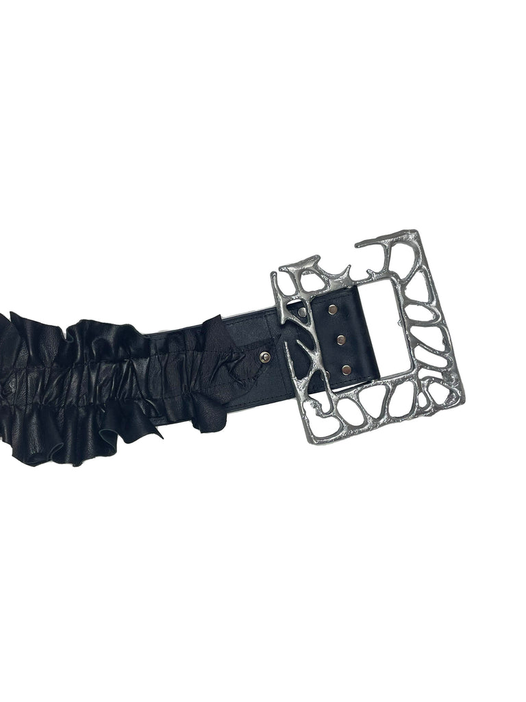 ruffled black leather belt with a very large silver aluminium organic frame shaped buckle on a plain background