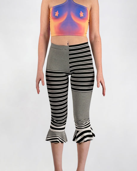 Person wearing a colorful top and black and white striped leggings on a white background