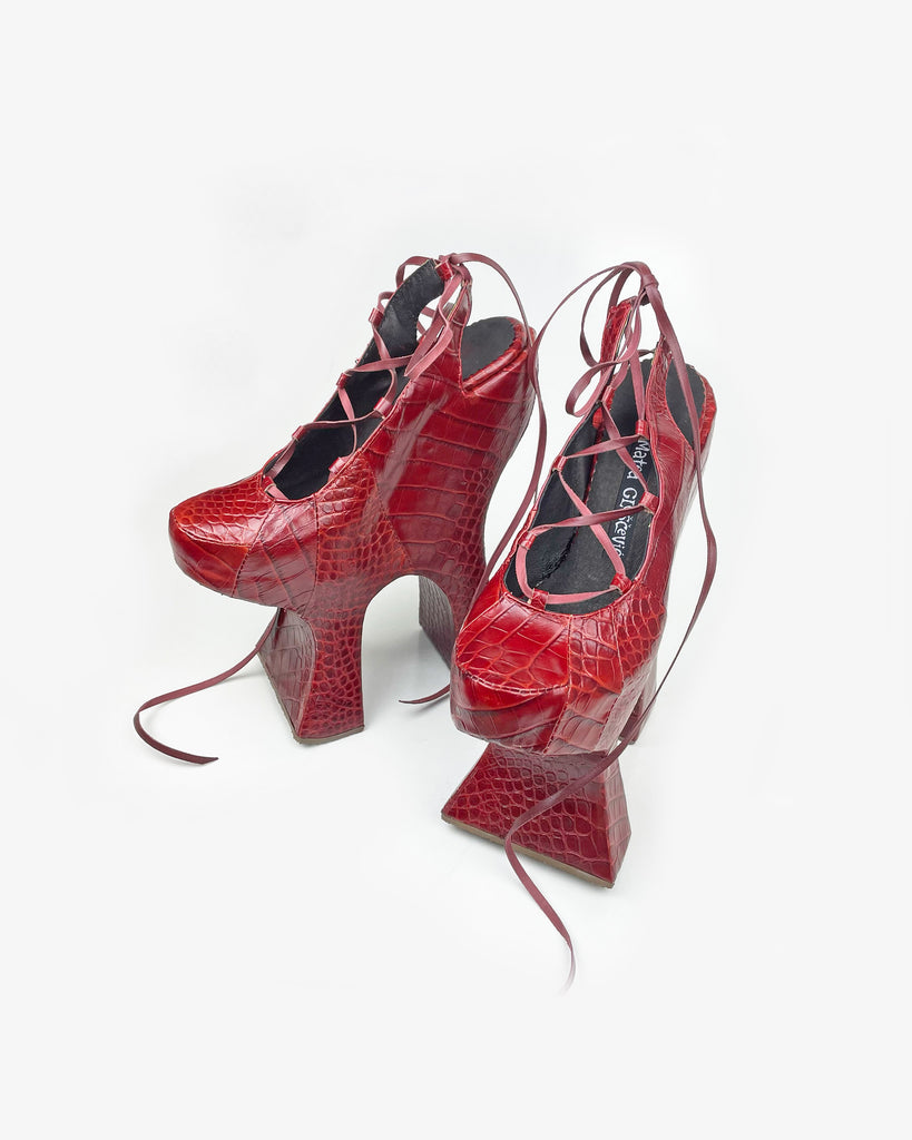 A red reptile print leather high heel chopine shoe with a platform sole and lace up front with exposed heel
