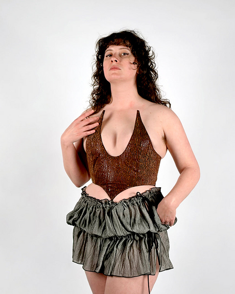 Woman wearing a brown corset and black ruffled skirt on a white background