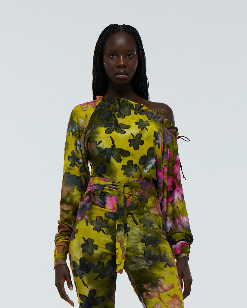 Model wearing a colourful green and pink floral tie dye patterned stretch long sleeve, drawstring neck top with high waist capri pants on a plain background