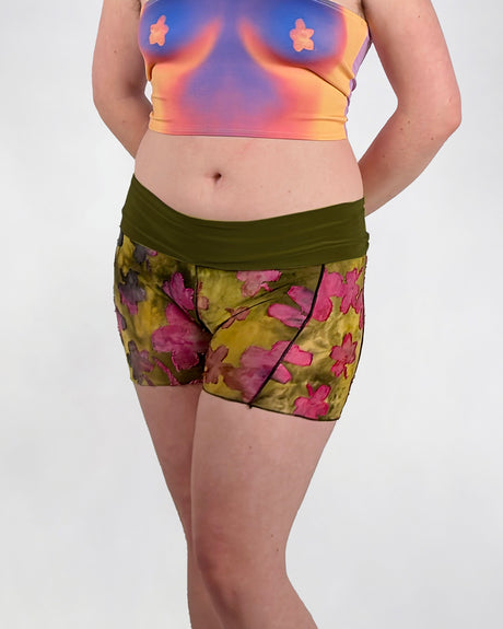 Person wearing a colorful top and floral shorts on a white background