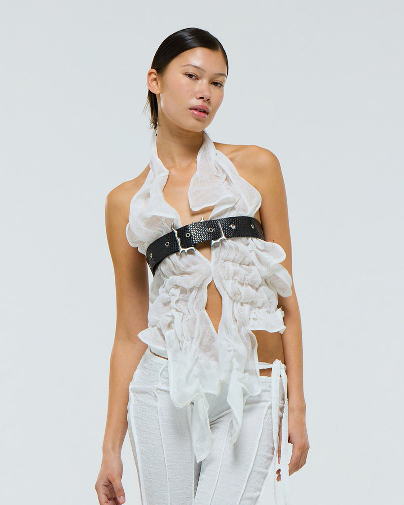 Model wearing a white outfit with a black reptile print leather belt on a plain background