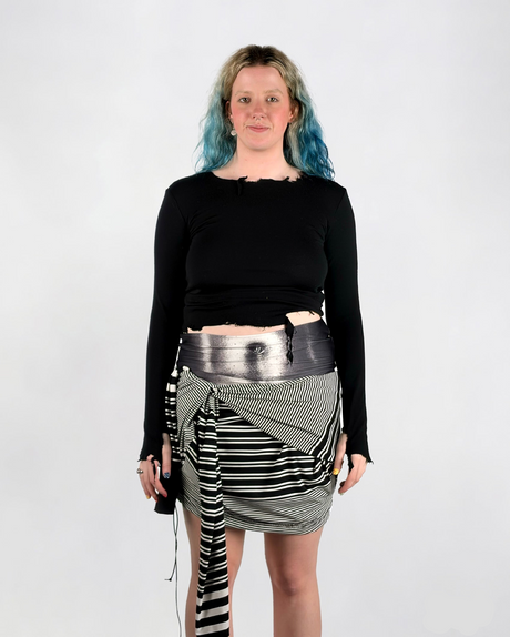 Person wearing a black long-sleeve wool top and a black and white striped skirt on a white background