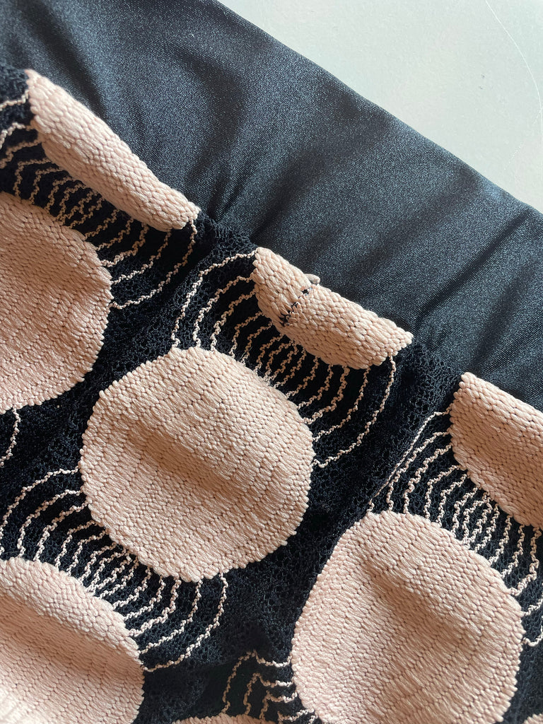 Close-up of a textured fabric with circular patterns in beige and black.