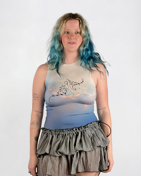 Person wearing a sleeveless top with a design and a ruffled skirt on a white background