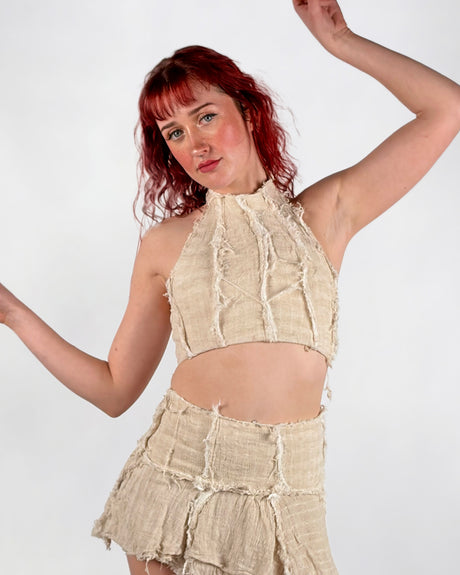 Woman wearing a beige halter top and skirt against a white background
