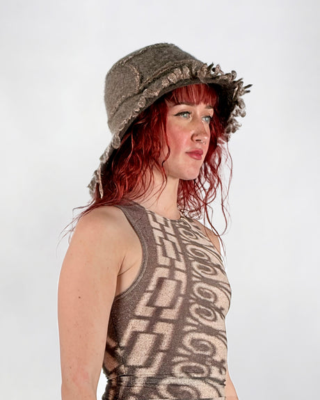 Woman wearing a patterned sleeveless top and brown wool hat against a white background